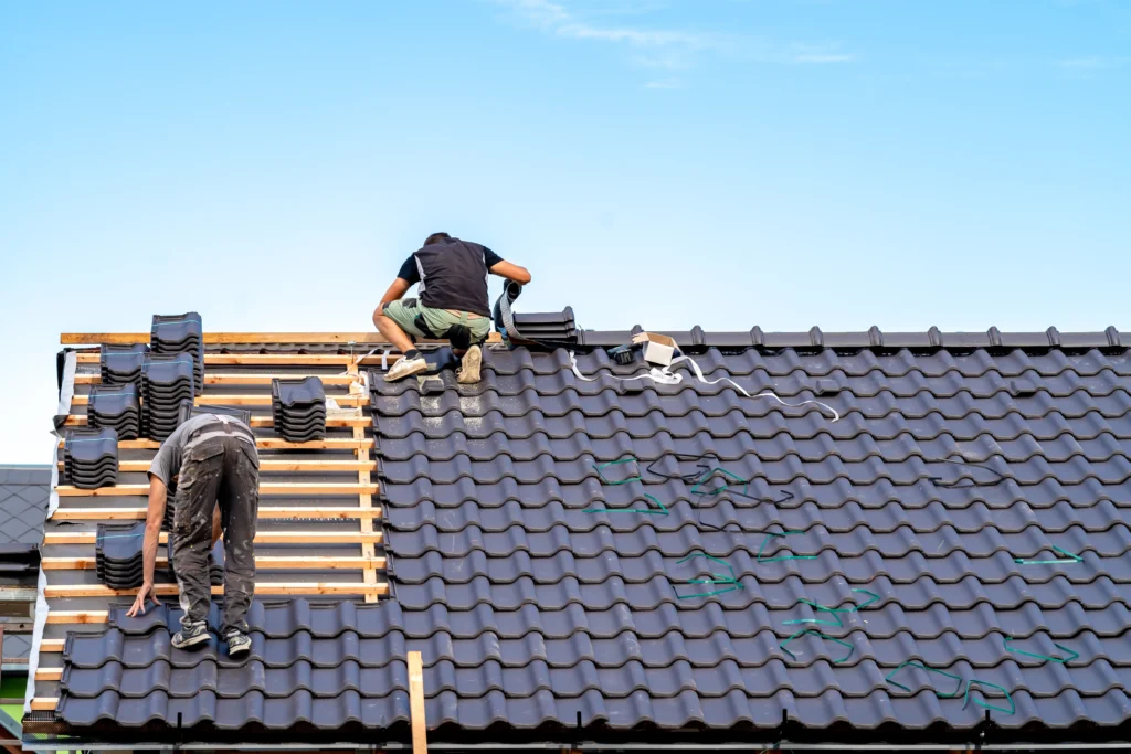 Roofing crew installs new ceramic tiles on a residential roof.