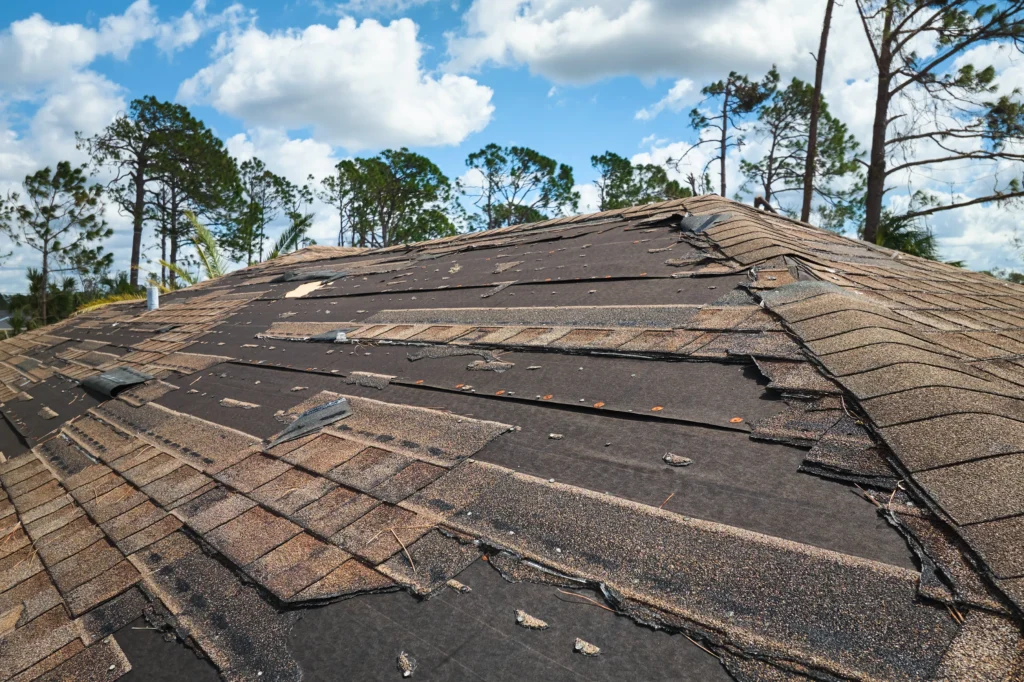 A damaged roof with missing shingles and exposed underlayment, highlighting the urgent need for roof replacement.